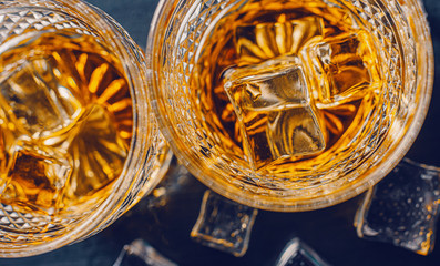 two expensive glasses of whiskey with ice on a black stone tray
