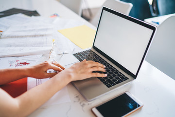 Faceless woman working on laptop at white table in office