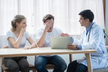 Unhappy caucasian young couple worried result of health illness examining after talking and discussion with expertise.Women shock men disappointment when doctor reading insurance plan.