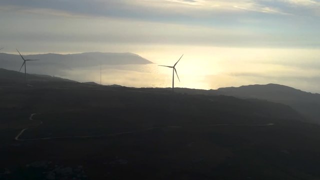 Aerial view of Silhouette of wind turbines at sunset with ocean on background near playa Barizo, La Coruna, Galicia Spain. Renewable energy. Drone footage pan from left to right