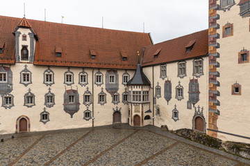 Fototapeta premium View of a corner of the backyard of the Hohes Scloss castle in Fussen on a cloudy winter day, with beautiful painting on facade, Allgaeu, Bavaria, Germany