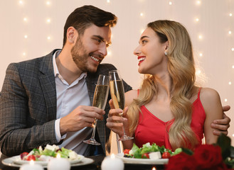Young Couple Having Romantic Evening In Restaurant, Clinking Glasses With Champagne