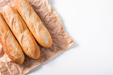 Freshly baked French baguettes on white wooden table.