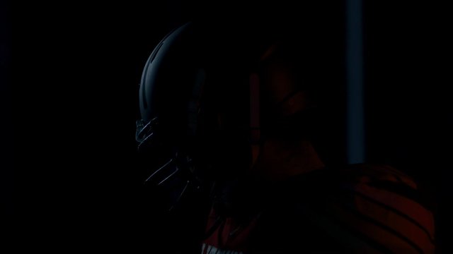 CU Portrait of American football player in protective uniform posing against bright flashing lights. Shot on ARRI Alexa Mini 60 FPS slow motion