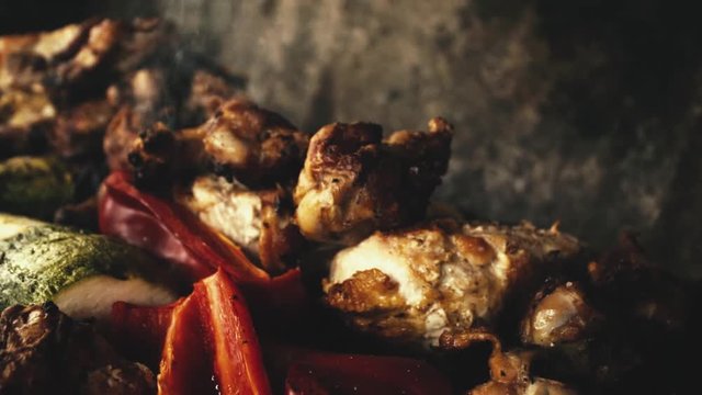 Slow-motion close-up chicken wings and grilled vegetables, (Italian squash and red pepper or red pepper / smoke from the charcoal grill).