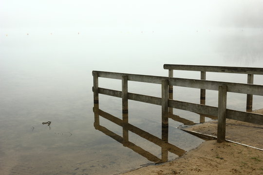 Foggy, wintery images of a lake: the Plas in Rotselaar in Flanders, Belgium. On the image a slope for disabled .