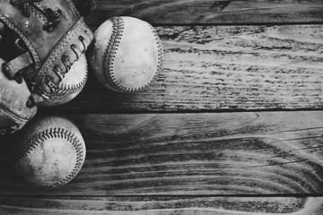 Grunge baseball background in black and white with group of balls and glove on wood texture.