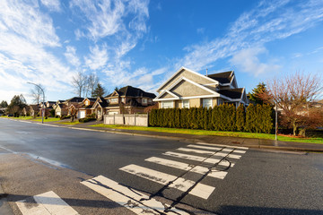 Obraz premium Crosswalk in a Residential Suburban Neighborhood during a vibrant winter sunrise. Taken in Fraser Heights, Surrey, Vancouver, BC, Canada. Wide Angle