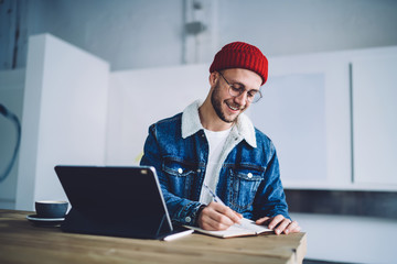 Hipster young man taking notes at office