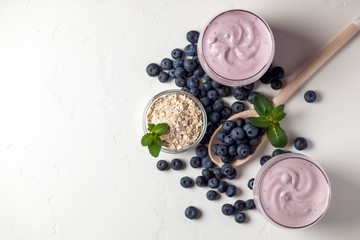 two fresh blueberry yogurt with blueberries and cereals on a white texture table, ingredients for cooking
