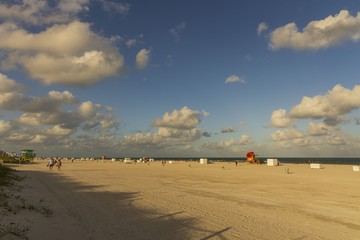 Sand beach, tourists and yellow lifeguard tower on blue Atlantic ocean merging with blue sky...