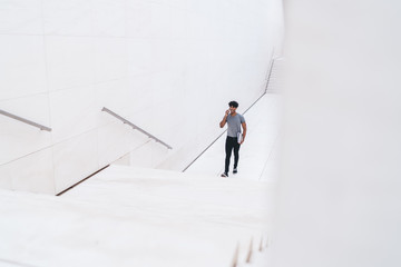 Man speaking on smartphone walking on white stairs