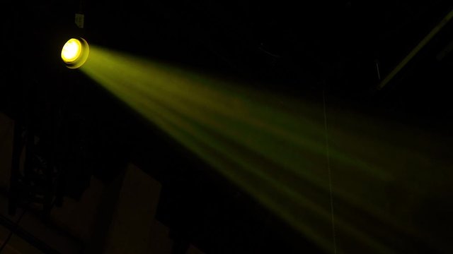 Yellow orange spot light creating a beam shining through some dustparticles and smoke from above and creating atmosphere great for background, with copy space.
