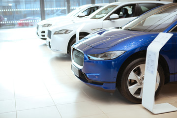 Cropped shot of a row of new cars at the dealership salon. Modern automobiles on sale at showroom, copy space