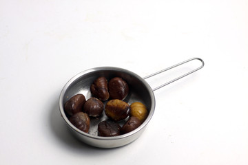 frying-pan of fried sweet chestnuts isolated on white background flat lay
