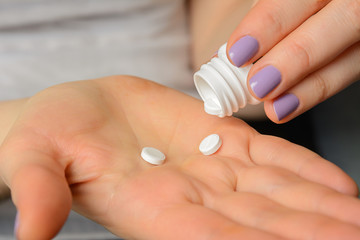 the person pours the pills medicine into the palm of his hand from the packaging of the bottle