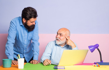 Obraz premium Male Multi Generation Family using Internet. Male workers chatting at office desk meeting. Businessman wearing shirt working with laptop at table.