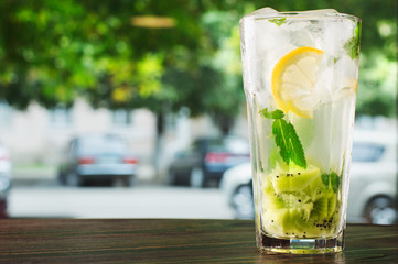 glass of water with ice and lemon on wooden table