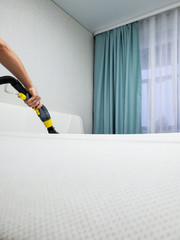Dry cleaning of the white mattress on the bed. Wet cleaning.