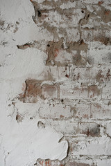 old brick wall painted with white paint and partially plastered