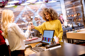 Happy woman customer paying with credit card in fashion showroom