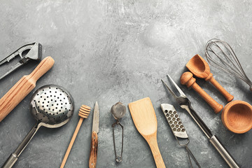 A variety of kitchen utensils and tools on a gray concrete rustic background. Top view, flat lay, copy space.