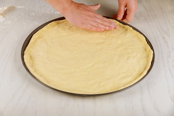 Fresh raw pizza dough in oven pan.