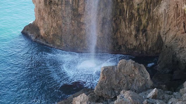 Medium shot, water fall on the rocky cliffs of Antalya, water bubbles rise from the sea.