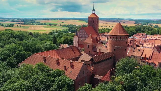 View from a drone on a historic, red-brick castle and church.
