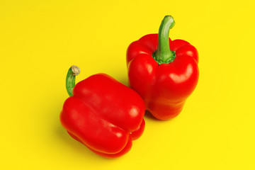 two red bell peppers on yellow background. close up