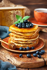 Pancakes with  berries and  honey on wooden  board