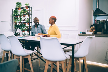 Smiling black colleagues chatting with each other at  table