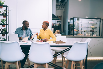 Black colleagues talking at table in cafe