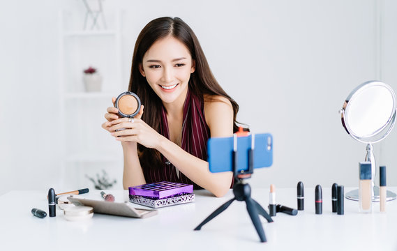 Portrait of young Asian beauty fashion vlogger or blogger doing a make up tutorial video online marketing with broadcasting live video to social network. Woman lifestyle cosmetic blogger concept.