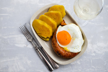 fried smoked portuguese sausage alheira with fried egg and sweet potato on white dish
