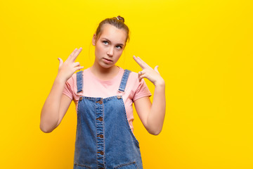 young blonde pretty girl crossing fingers anxiously and hoping for good luck with a worried look...