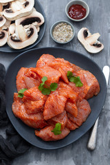 raw meat with spices on dark dish on ceramic background