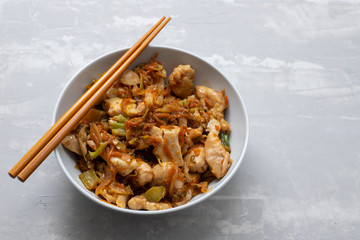 chicken with vegetables in white bowl on ceramic background