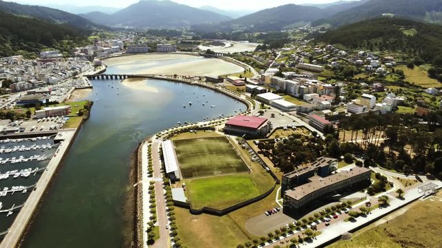 Aerial drone view of Viveiro village and marina and the beautiful beach of Covas just nearby during a sunny summer daytime with the vast mountains in the background