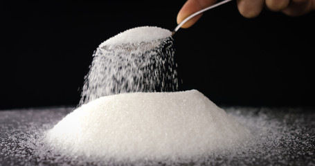 Sugar or Salt taken with Spoon from a bowl at closeup