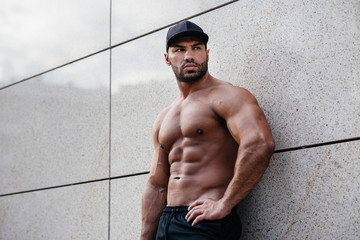 sexy sportsman stands topless near the wall. Fitness, bodybuilding