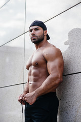 sexy sportsman stands topless near the wall. Fitness, bodybuilding