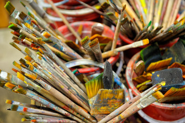 Obraz premium Collection of used paintbrushes with colorful stains.