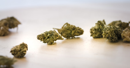 Medical Marijuana Buds falling on wooden background. Dried Cannabis Plant closeup