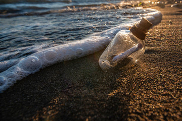 Bottle with a message in the sea at sunset