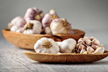 Garlic Cloves and Bulb in wooden bowl on white table.