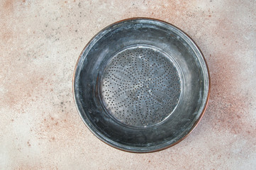 Antique copper sieve on concrete background.