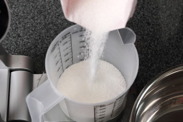 Pouring Sugar into Measuring Cup on Kitchen Scale. Making Golden Syrup Series.