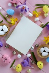 Easter Flat Lay.empty diary and easter decorative eggs in nests, spring flowers crocuses m daffodils on a pink background.top view, copy space.Easter trendy background.Easter holiday