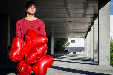 A guy with heart-shaped balloons on Valentine's Day. The guy in the red jacket